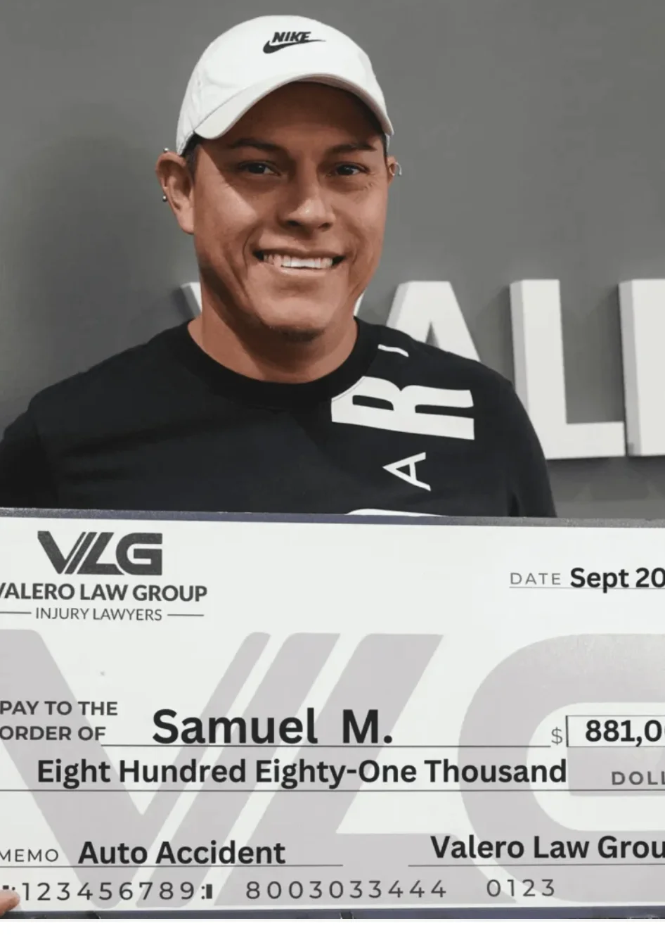 Valero Law Group client Samuel M. holding a $881,000 auto accident settlement check