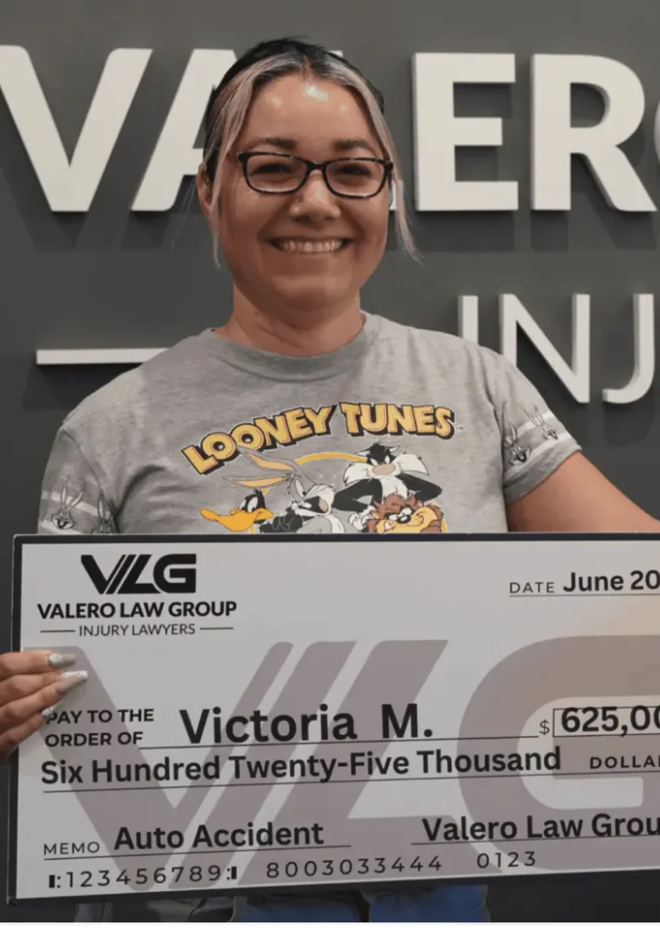 Valero Law Group client Victoria M. holding a $625,000 auto accident settlement check
